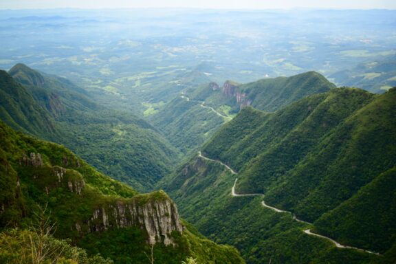 A winding road traverses the verdant Serra do Rio do Rastro in Santa Catarina, Brazil, offering mountain and valley views.