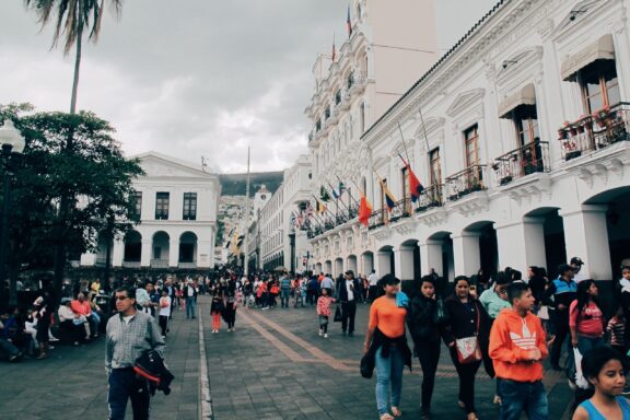 A bustling street scene in Quito, Ecuador with people walking and colonial buildings lining the street.