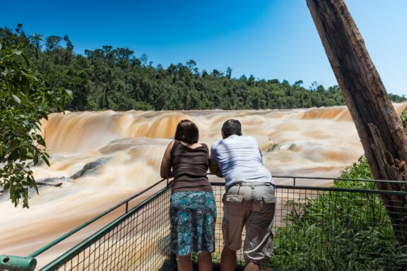 Two people standing at a viewpoint observing the Saltos del Monday waterfalls in Paraguay.