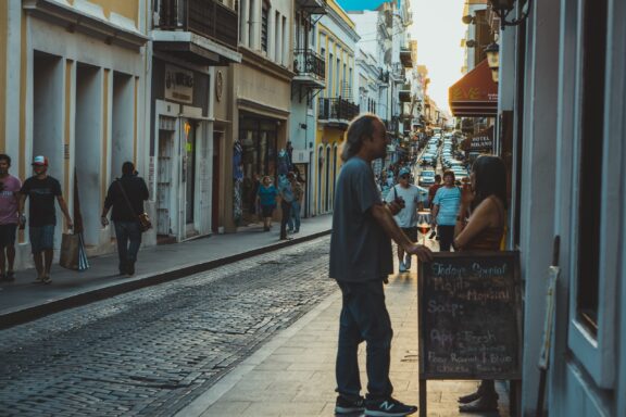 A street scene in San Juan, Puerto Rico, featuring people walking and a couple interacting near a shopfront.