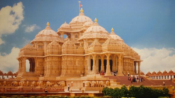 A photo of the Akshardham Temple with intricate carvings, under a blue sky with light clouds.