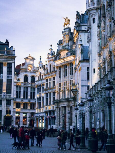 An image of the Grand Place in Brussels during twilight with people gathered and historic buildings illuminated in the background.