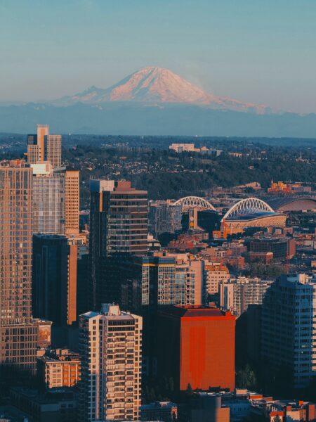 A view of Seattle, Washington, with skyscrapers in the foreground and Mount Rainier in the background under a clear sky.