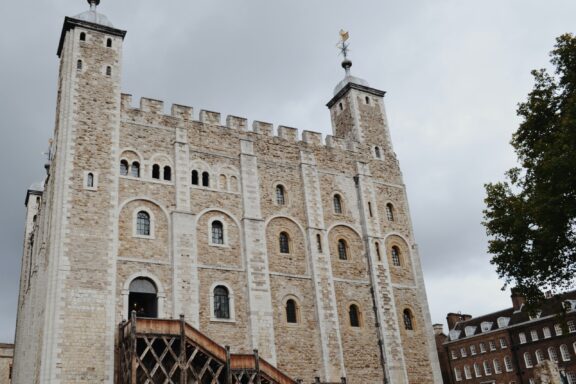 A photograph of the Tower of London, featuring the historic stone fortress with a cloudy sky in the background.