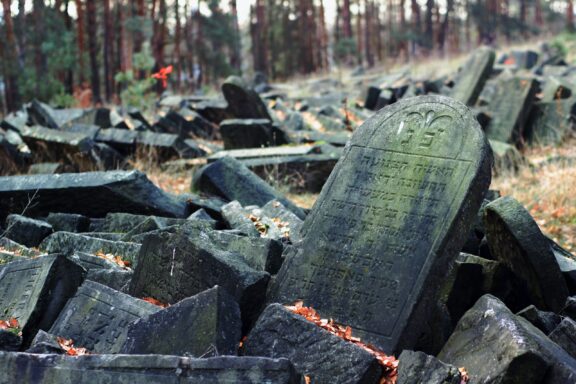 A weathered Jewish gravestone amidst fallen and broken tombstones in the Warsaw Jewish Cemetery.