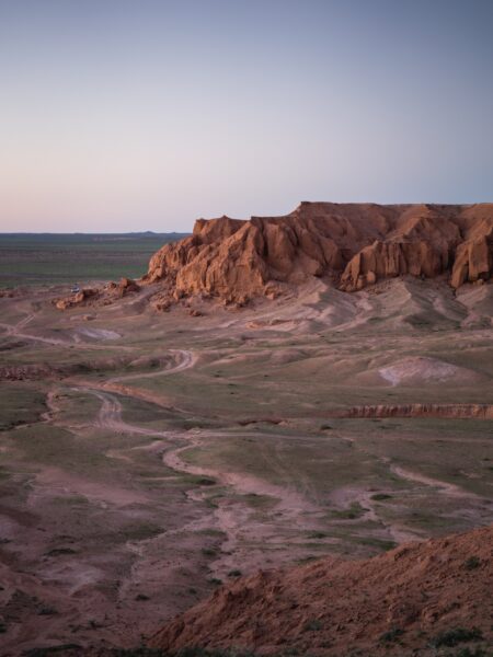 A photo of a rocky outcrop in the Bulgan region of Mongolia during twilight, with vast open plains in the foreground.