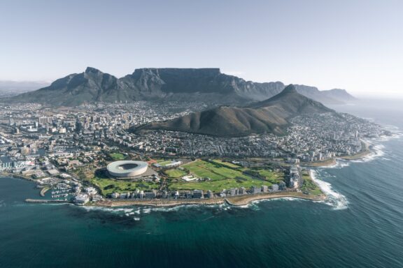 Aerial view of Cape Town, South Africa, featuring Table Mountain in the background, the cityscape, and the coastline.