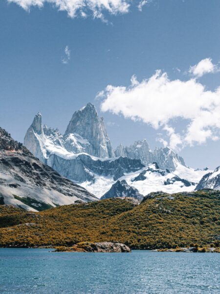 A scenic view of El Chaltén in Santa Cruz, Argentina, featuring a lake in the foreground with mountains and a clear blue sky in the background.