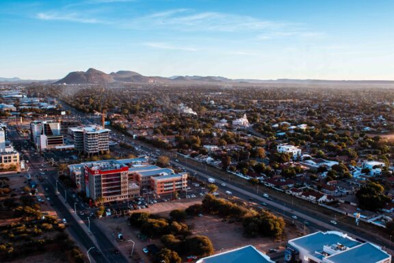 Aerial view of Gaborone, Botswana, showing buildings, roads, and landscape during twilight.