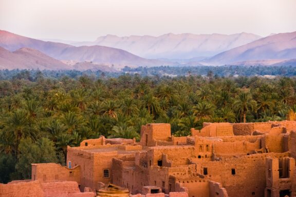 The ancient Moroccan village of Tamnougalt boasts traditional earthen architecture, nestled among palm groves and mountains.