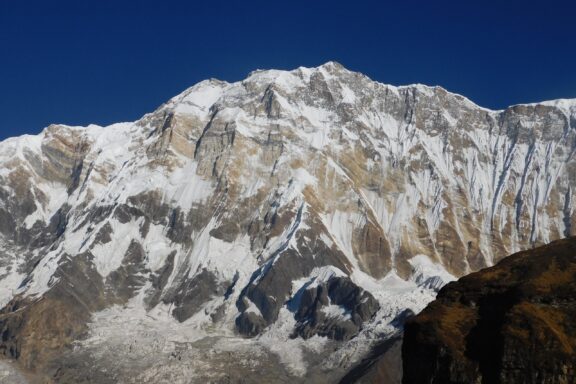 A view of the snow-covered Annapurna I mountain under a clear blue sky.