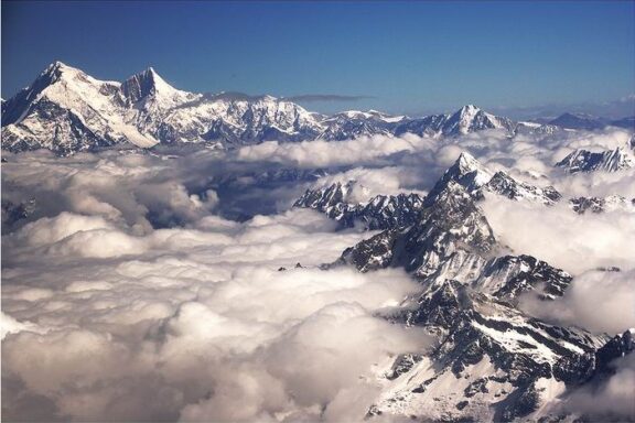 Aerial view of the snow-covered peaks of Gosainthan (Shishapangma) with clouds blanketing the lower elevations.