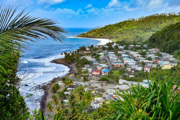 A picturesque coastal view of Saint Vincent and the Grenadines, with a vibrant town between green hills and the blue sea.