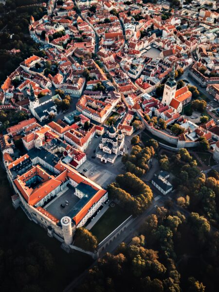 Aerial view of Tallinn Old Town, Estonia displays historic architecture, red-tiled roofs, narrow streets and green surroundings.