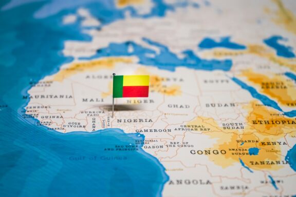 The flag of Benin pinned on the location of Benin in West Africa