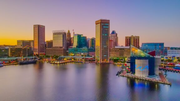 An image of the Baltimore, Maryland skyline during sunset with reflections on the water.