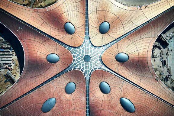 Aerial view of Beijing Daxing International Airport's starfish-shaped terminal building with a unique roof design.