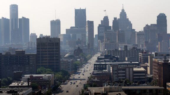 A hazy skyline view of Detroit, Michigan, featuring various buildings and skyscrapers under a light sky.