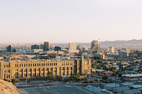 A cityscape of El Paso, Texas, with diverse buildings under a clear sky at sunrise or sunset.