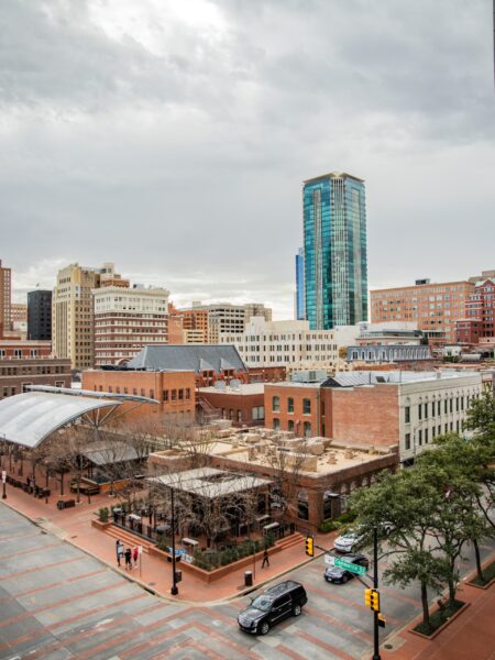 A view of downtown Fort Worth, Texas, featuring a mix of historic and modern buildings under an overcast sky.