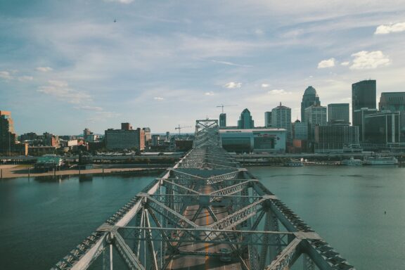 A picture of Louisville, Kentucky, showcasing a bridge leading to the city skyline under a partly cloudy sky.