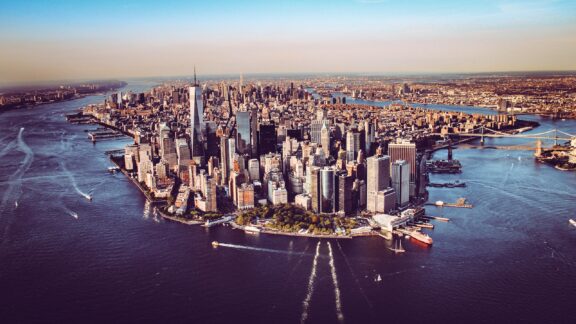 Aerial view of Manhattan, New York City, showcasing the dense skyline with numerous skyscrapers and the surrounding waterways.