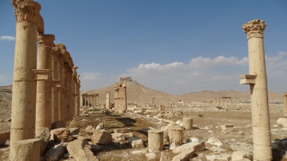 Ancient columns and ruins at Palmyra in the Syrian Desert under a clear sky.