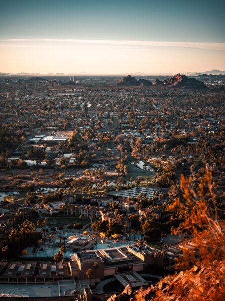 Aerial view of Phoenix, Arizona during sunset with buildings and landscape bathed in warm light.