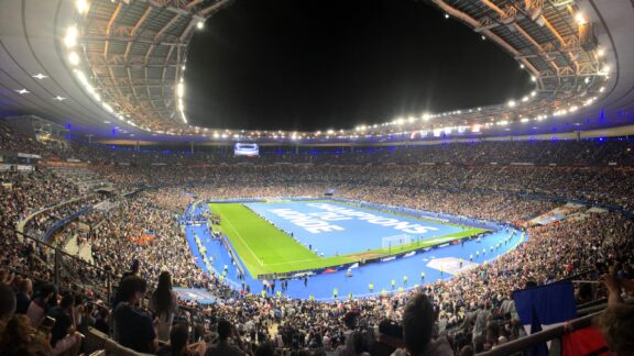 A full house sits in Stade de France during an event at night.