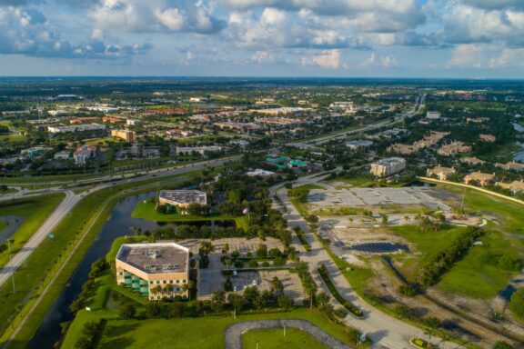 Aerial shot of Port St. Lucie, Florida, displays a suburban layout with homes, roads, greenery, and some commercial structures.