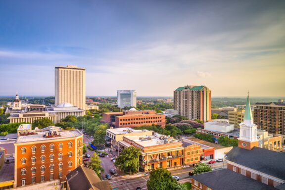 Aerial view of downtown Tallahassee, Florida, showcasing a mix of modern and historic buildings under a soft sky at dusk.