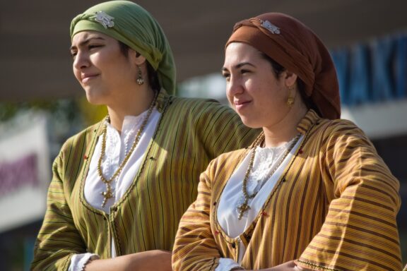 Traditional Greek Cypriot Women in Folk Costumes Two Greek Cypriot women in traditional dress, smiling and posing for a photo.