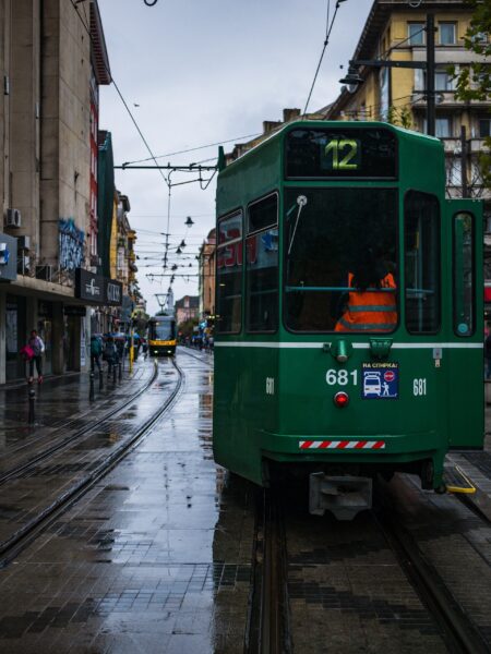 A green tram with the number 681 on a wet street with tramlines in Sofia, Bulgaria, with pedestrians on the sidewalks and overcast skies above.