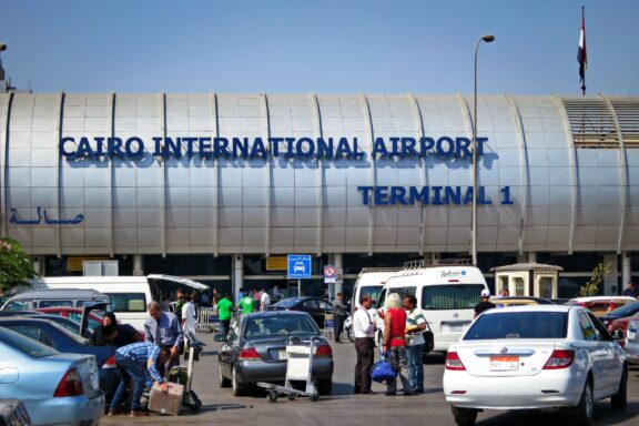 A busy scene in front of Cairo International Airport Terminal 1 with cars and people.