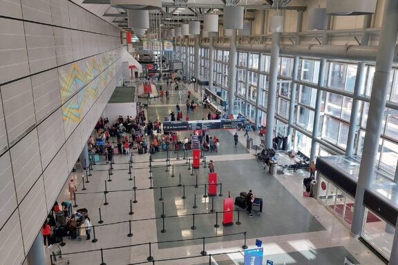 Interior view of Houston International Airport with travelers in queue lines and check-in counters.