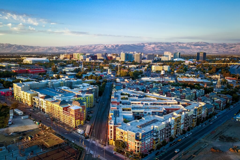 Aerial shot of San Jose, California, displaying a blend of residential and commercial structures with mountains behind.