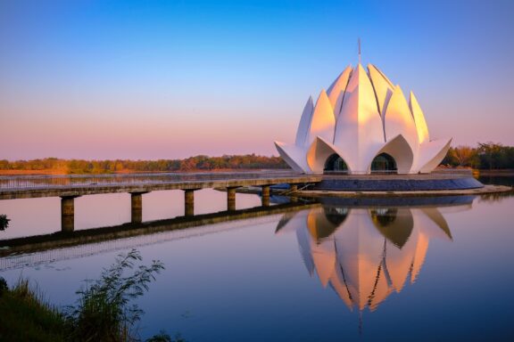 A serene sunset view of the Lotus Temple in Udon Thani, Thailand, with its reflection in the water.