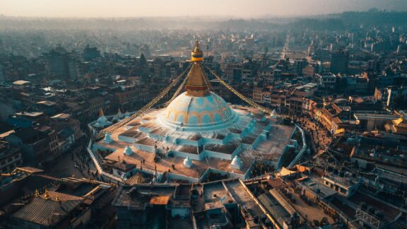 Aerial view of Boudhanath Stupa with surrounding buildings at dusk, Kathmandu, Nepal.