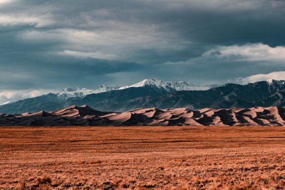 Sand dunes can be seen in front of mountains in Great Dunes National Park, Colorado.