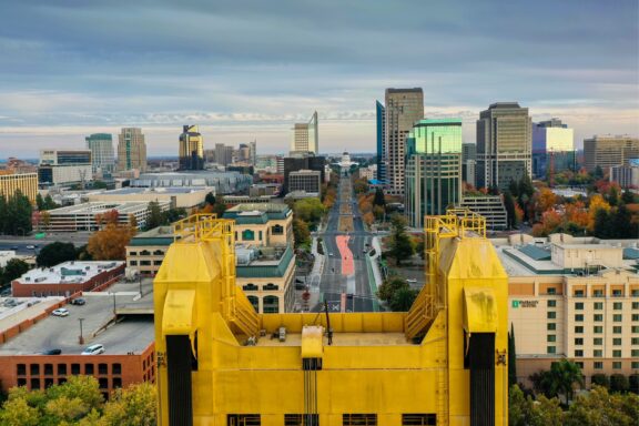 Aerial view of downtown Sacramento, California, with buildings and streets visible under a cloudy sky.