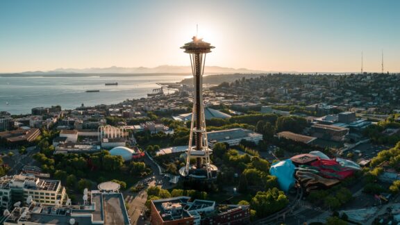 Aerial view of the Seattle Space Needle with the cityscape and water in the background during daylight.