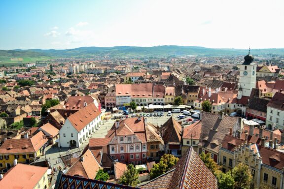 Aerial view of Sibiu, Romania, showcasing the historic town center with red-roofed buildings and the surrounding landscape.