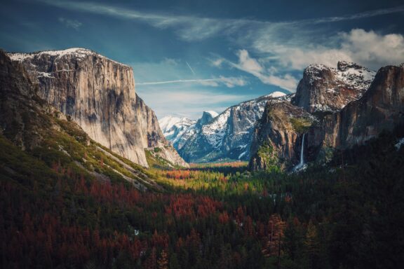 Tunnel View in Yosemite National Park, California showcases granite cliffs, a forested valley, and snowy mountain peaks.