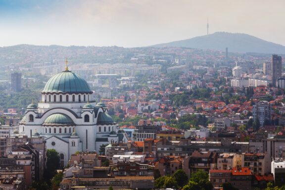 Aerial view of Old Belgrade, featuring the Saint Sava Temple, with the cityscape and hills in the background.