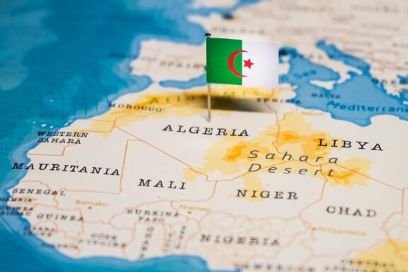 An Algerian flag pin marking the country's location, emphasizing its global presence