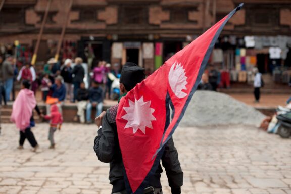 A person carrying the national flag of Nepal in a local area of Kathmandu.