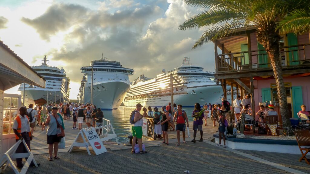 A busy port in St. John's, Antigua, featuring a street market, palm trees, and docked cruise ships.