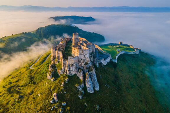 Aerial panoramic view of the Spiš Castle, Slovakia, in the morning sunlight with foggy background and Tatra Mountains seen on the horizon.