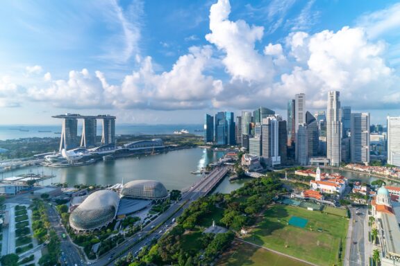 Aerial view of Marina Bay in Singapore on a cloudy day, showcasing the iconic Marina Bay Sands, the ArtScience Museum, and surrounding skyscrapers.