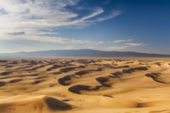 A beautiful view of the rolling sand dunes under a blue sky in the Gobi Desert, Mongolia.